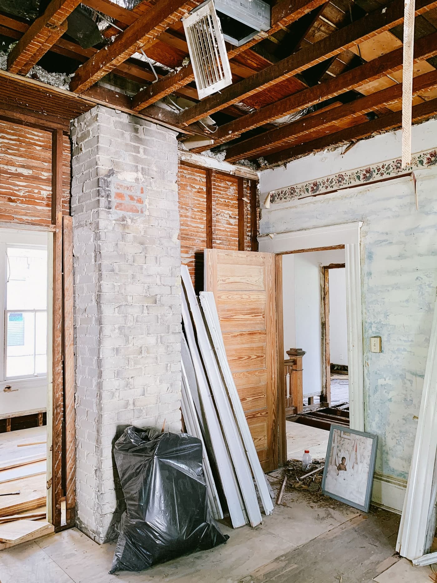 A panelled timber door and lengths of trim stand beside painted brickwork in a room under renovation.